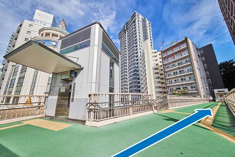 歩道橋を上がったら、矢印の方向へ進みます。（階段の場合、左折です。）